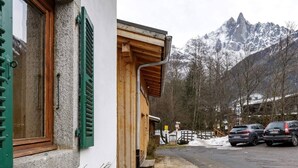 A mountain lodge with a wooden exterior, a wooden door, and a view of snow-covered mountains. - Vouvy - Moderne 4pax | Remontée Flégère 5min | Praz | Arve (Chamonix-Mont-Blanc)