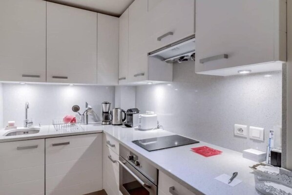 A modern kitchen with white cabinets, a stainless steel sink, and a black countertop.