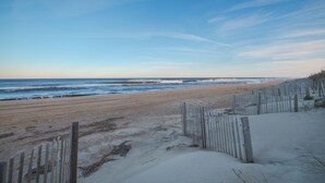 A beach with a wooden fence and waves in the background. - 5201 - Flip Flop Time - Cozy Oceanfront Condo | OBX Getaway (Kill Devil Hills)