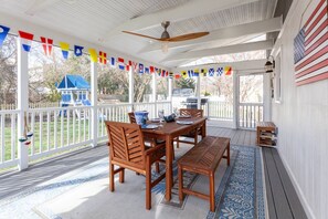 A covered patio with a wooden table and chairs, a ceiling fan, and a view of a backyard with a play structure. - Ahoy! Game Room, Screened Porch, Yard Mins to DTA (Annapolis)