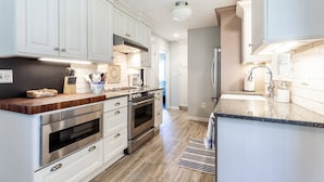 A modern kitchen with white cabinetry, stainless steel appliances, and a wooden countertop. - Ahoy! Game Room, Screened Porch, Yard Mins to DTA (Annapolis)
