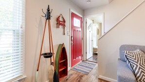 A hallway with a red door, a wooden floor, a grey sofa, and a tripod lamp. - Ahoy! Game Room, Screened Porch, Yard Mins to DTA (Annapolis)