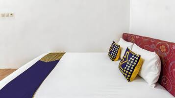 A bed with a white mattress, a blue and yellow patterned bedspread, and two pillows with similar patterns.