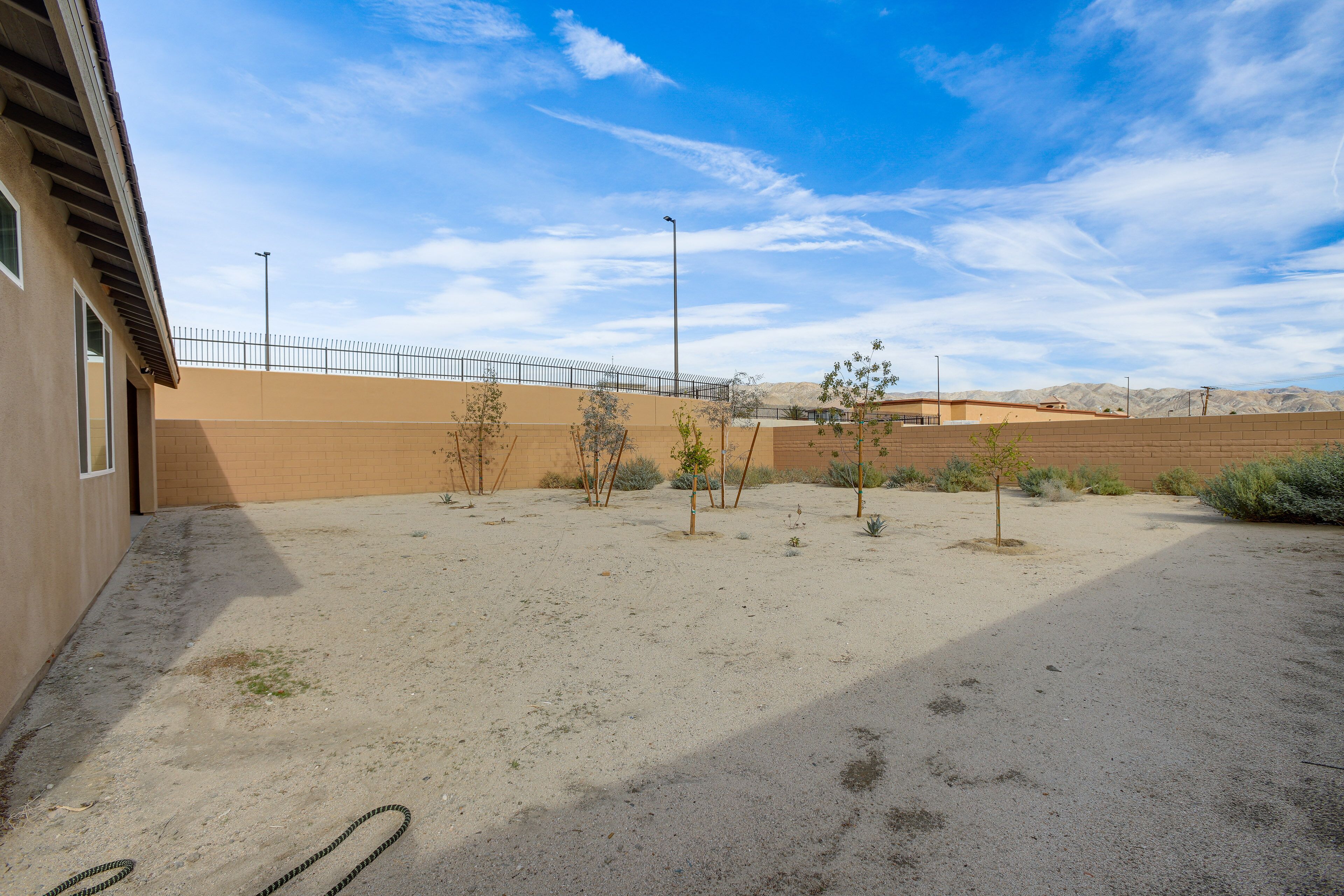 A desert landscape with a building, a fenced area, and sparse vegetation.