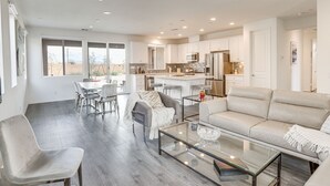 A spacious living area with a glass coffee table, a sofa, and a dining table with chairs. - Desert Hot Springs Vacation Home w/ Community Pool (Desert Hot Springs)