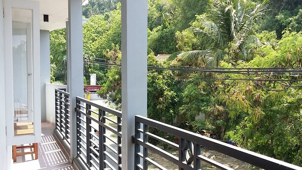 A balcony with a metal railing, a wooden chair, and a small table.