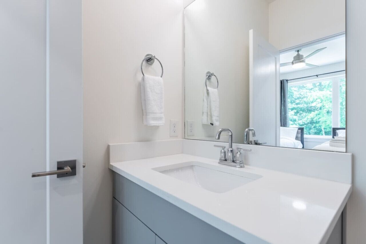 Une salle de bain moderne avec un lavabo blanc, un miroir et un porte-serviettes.