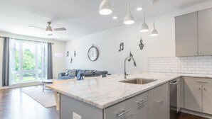 Una cocina moderna con una isla central, muebles grises e iluminación colgante.