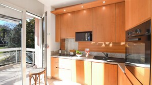 A modern kitchen with wooden cabinets, a microwave, and a stainless steel refrigerator. - Sweet Lake View Lugano (Lugano)