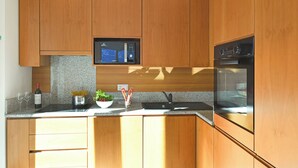 A kitchen with wooden cabinets, a built-in microwave, and an oven. - Sweet Lake View Lugano (Lugano)