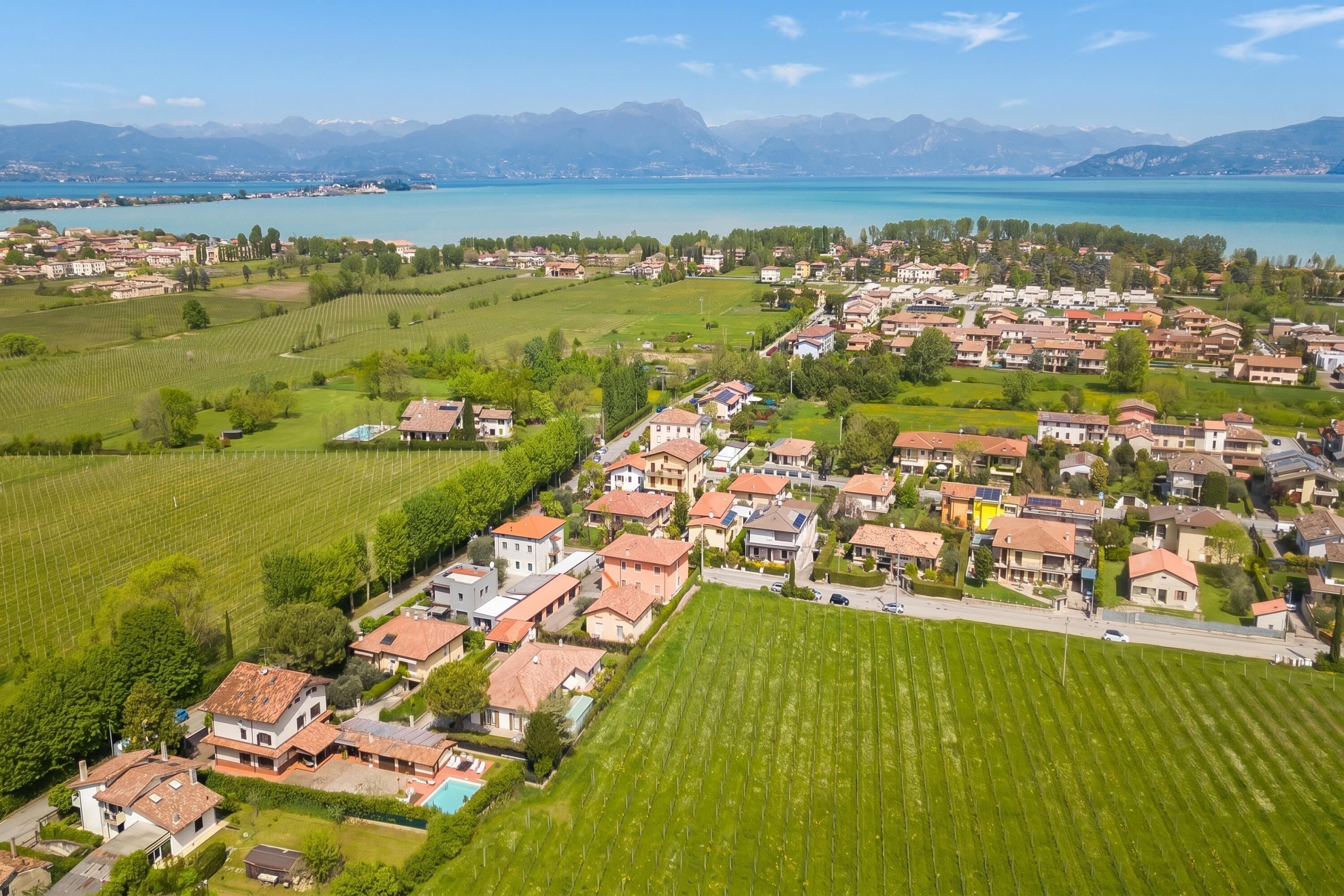 Un quartier résidentiel avec des maisons, des champs verdoyants et un lac.