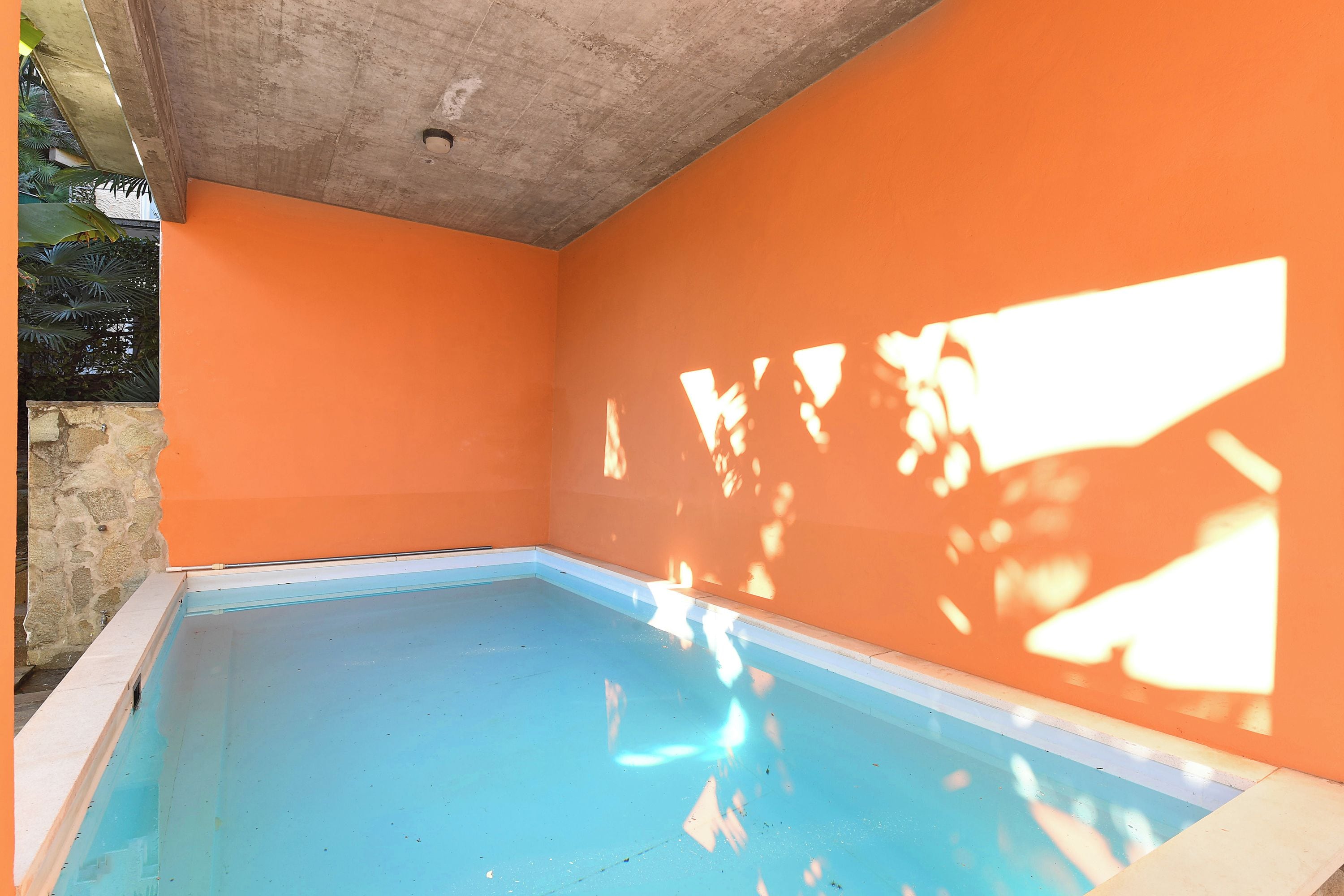 Una piscina interna con soffitto in cemento e pareti arancioni.
