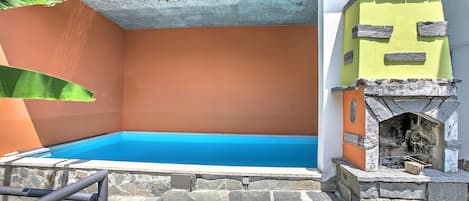 A swimming pool with a stone deck, a stone fireplace, and a concrete ceiling.