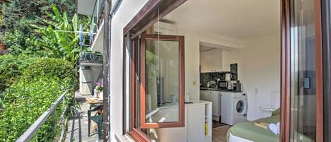 A modern apartment with a balcony, a kitchen, a washing machine, and a bed.