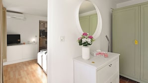 A bedroom with a white dresser, a mirror, and a vase with flowers. - Studio W/panoramic View, Shared Pool, Garden & Terrace (Agno)