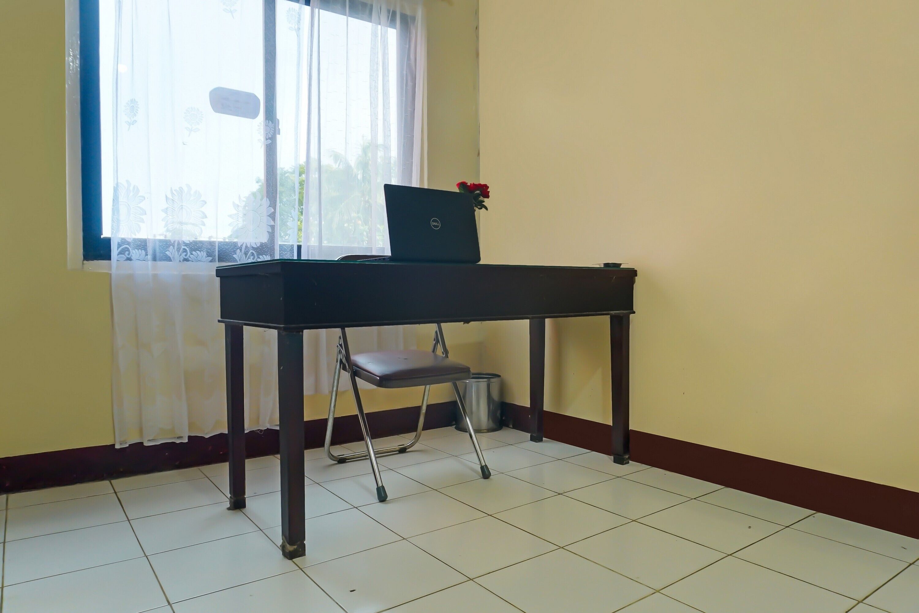 Una habitación con escritorio, silla y una laptop adornada con flores.