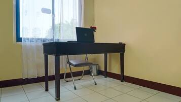 Una habitación con escritorio, silla y una laptop adornada con flores.
