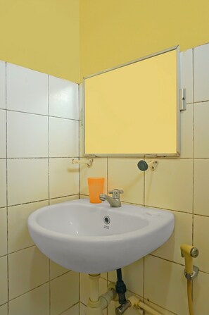 Bathroom with a sink, mirror, and yellow-tiled wall.