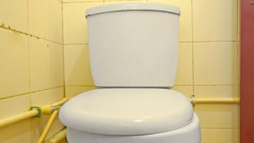 Un inodoro blanco en un baño con paredes y suelo de baldosas amarillas.