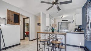 A modern kitchen with a bar area, white cabinets, and a ceiling fan. - Appaloosa - Unit A (Colorado Springs)