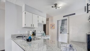 A modern kitchen with granite countertops, white cabinets, and stainless steel appliances. - Appaloosa - Unit A (Colorado Springs)