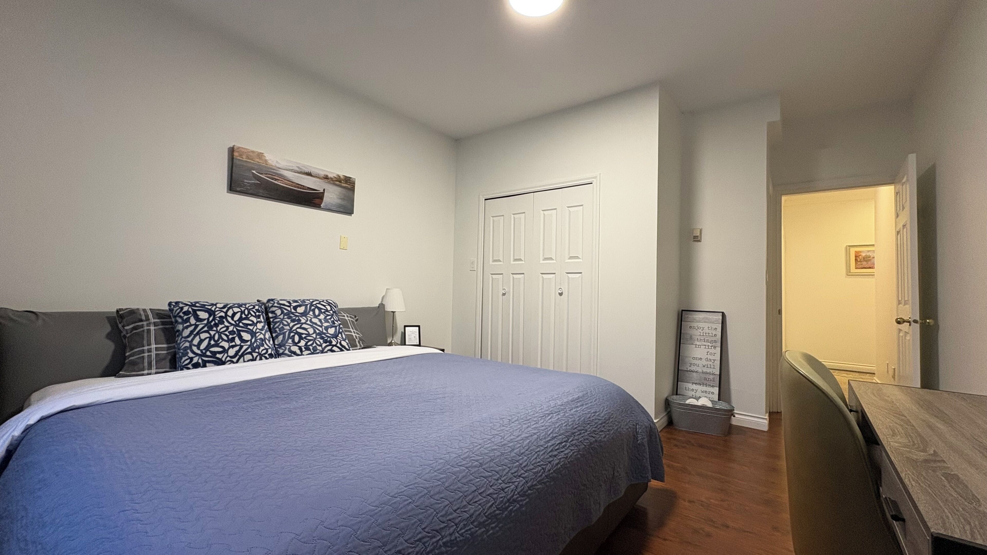 Une chambre à coucher avec un lit, une table de chevet, une commode, une armoire et un tableau accroché au mur.