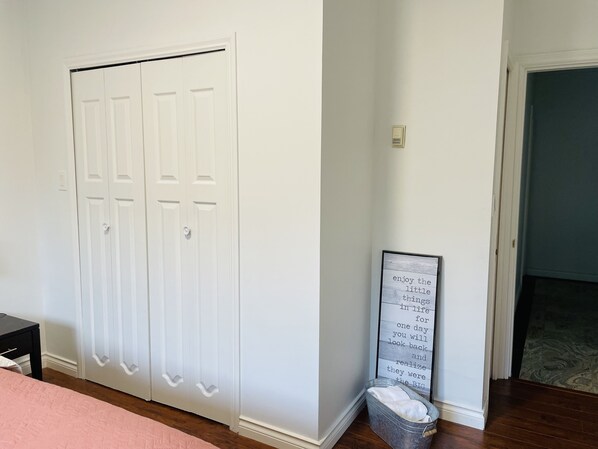 Una habitación con una puerta blanca, una cita inspiradora en un marco en la pared y un pequeño cubo de basura.