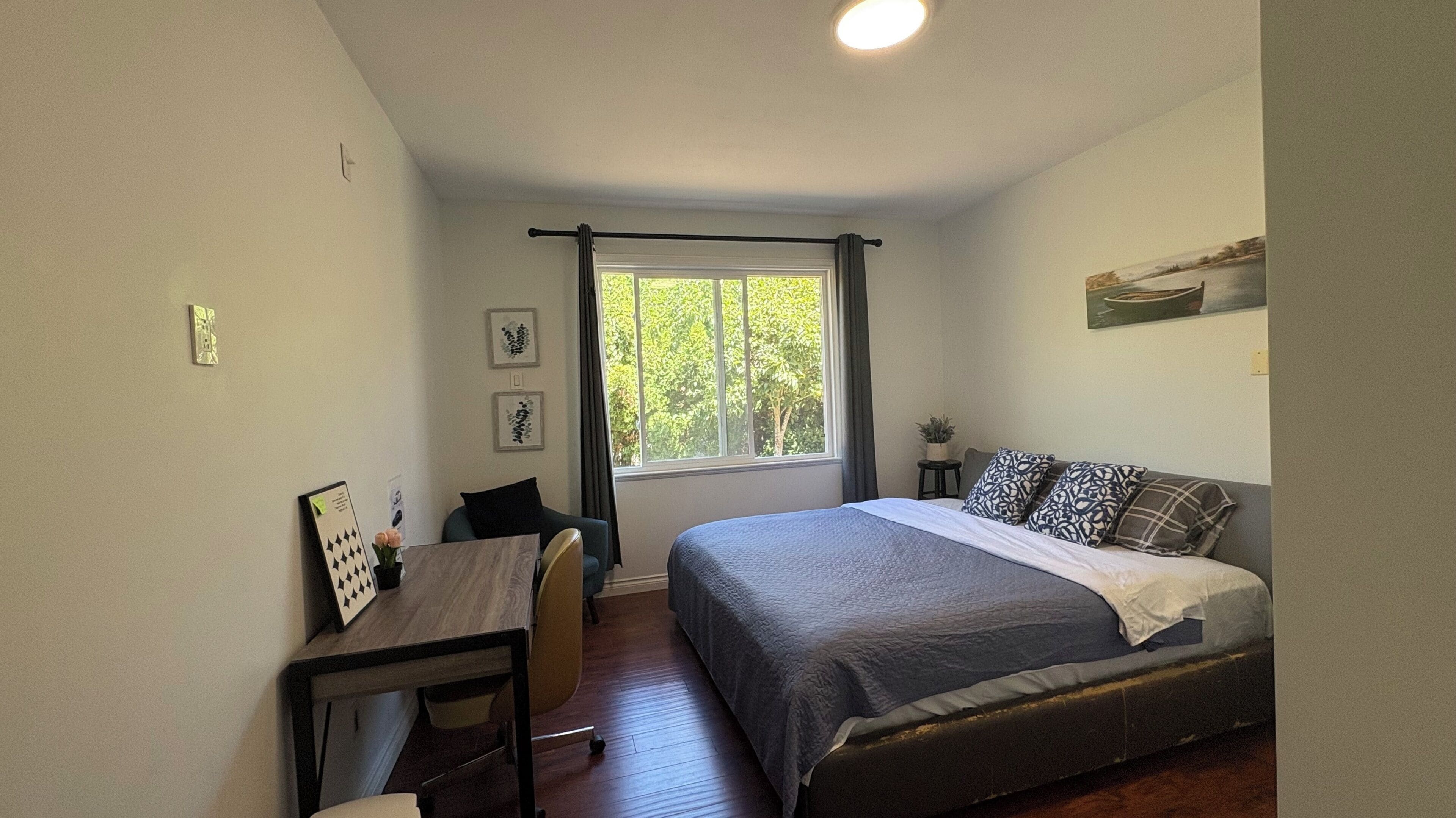 Quarto com cama, escrivaninha e janela.