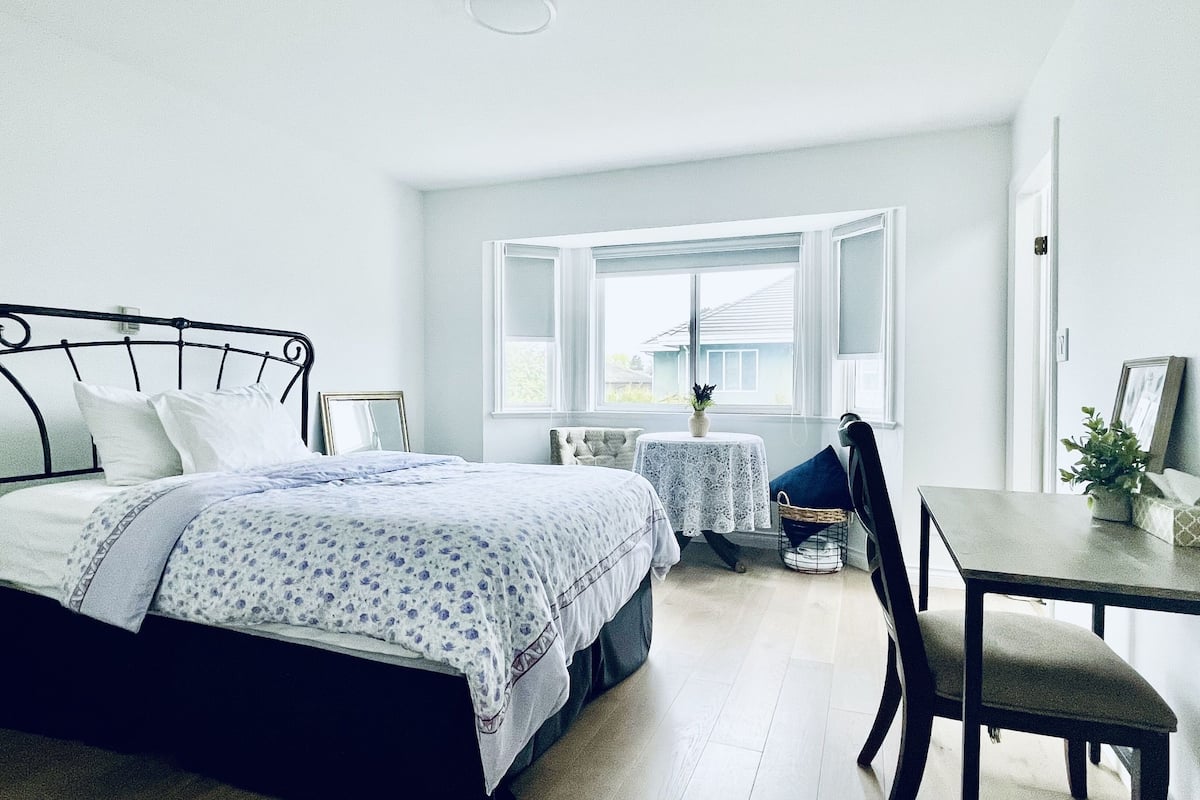 Ein Schlafzimmer mit Bett, kleinem Tisch, Stuhl und Fenster.
