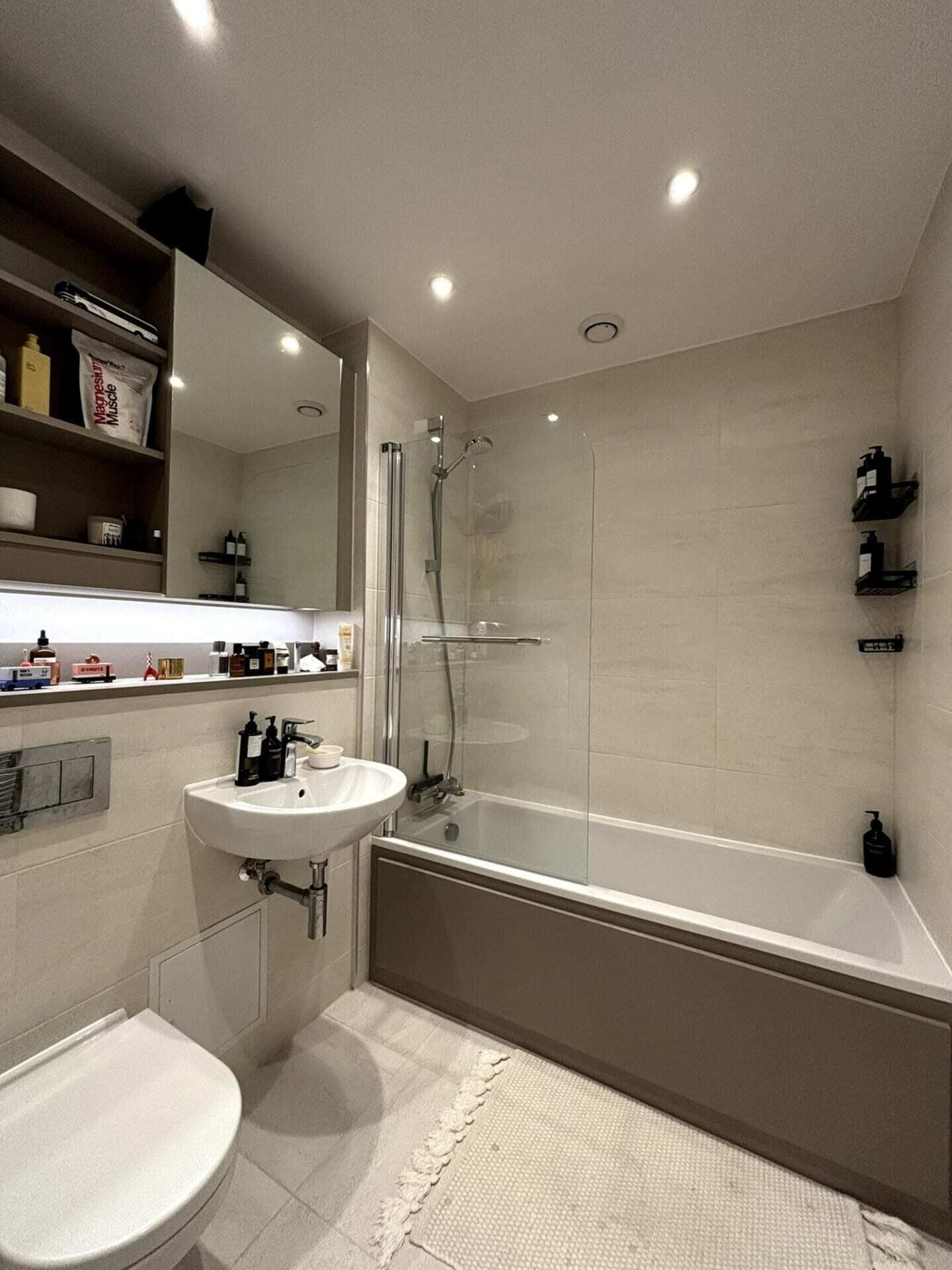 A modern bathroom with a shower, sink, and toilet.