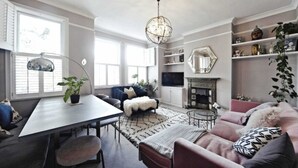 A cozy living room with a fireplace, a dining area, and a large window.
