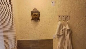 A bathroom with a large bathtub, a Buddha statue, a towel rack, and a bottle of champagne. - Recanto Zen (Imbituba)