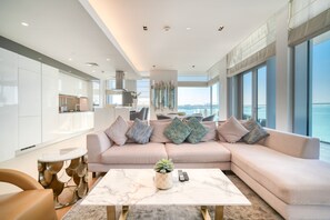 Ein modernes Wohnzimmer mit einer großen Eckcouch, einem Marmortisch und Blick auf die Stadt.