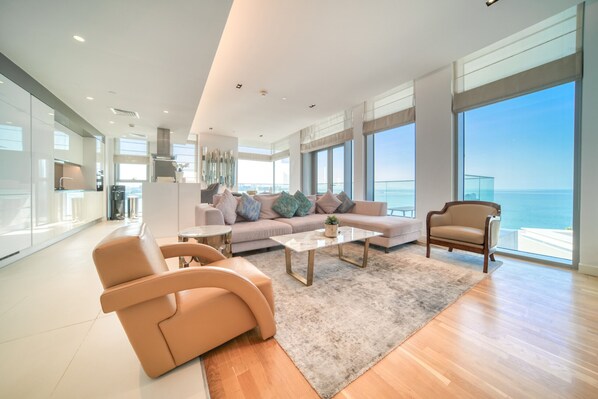 Ein geräumiges Wohnzimmer mit einer großen Couch, einem Couchtisch und Blick auf den Ozean.