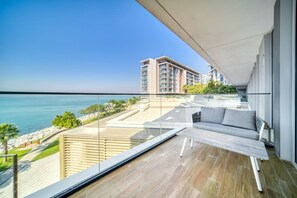 A modern balcony with a view of the sea, a wooden deck, and a sofa.
