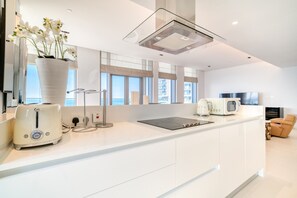 A modern kitchen with a central island, a built-in oven, and a microwave.