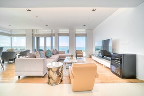 Ein modernes Wohnzimmer mit einer Couch, Sesseln, einem Couchtisch und einem Fernseher.