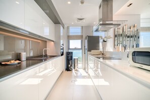 Eine moderne Küche mit glatten Schränken, einem eingebauten Backofen und einem großen Fenster mit Blick ins Freie.