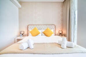 A hotel room with a large bed, two bedside lamps, and a water bottle on the nightstand.