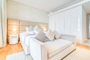 Ein modernes Schlafzimmer mit einem großen Bett, einem weißen Kleiderschrank und einem Nachttisch mit Lampe.