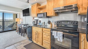 A modern kitchen with wooden cabinets, a stainless steel oven, and a microwave. - Mid-Nest Unit 708 (Colorado Springs)