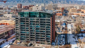 A high-rise building with multiple floors, a parking lot, and a mountainous backdrop. - Mid-Nest Unit 708 (Colorado Springs)