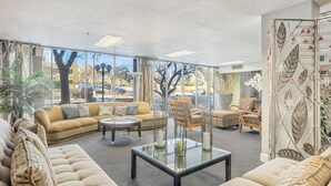 A spacious living area with a sofa, chairs, and a coffee table. Large windows provide a view of the outdoors. - Mid-Nest Unit 708 (Colorado Springs)