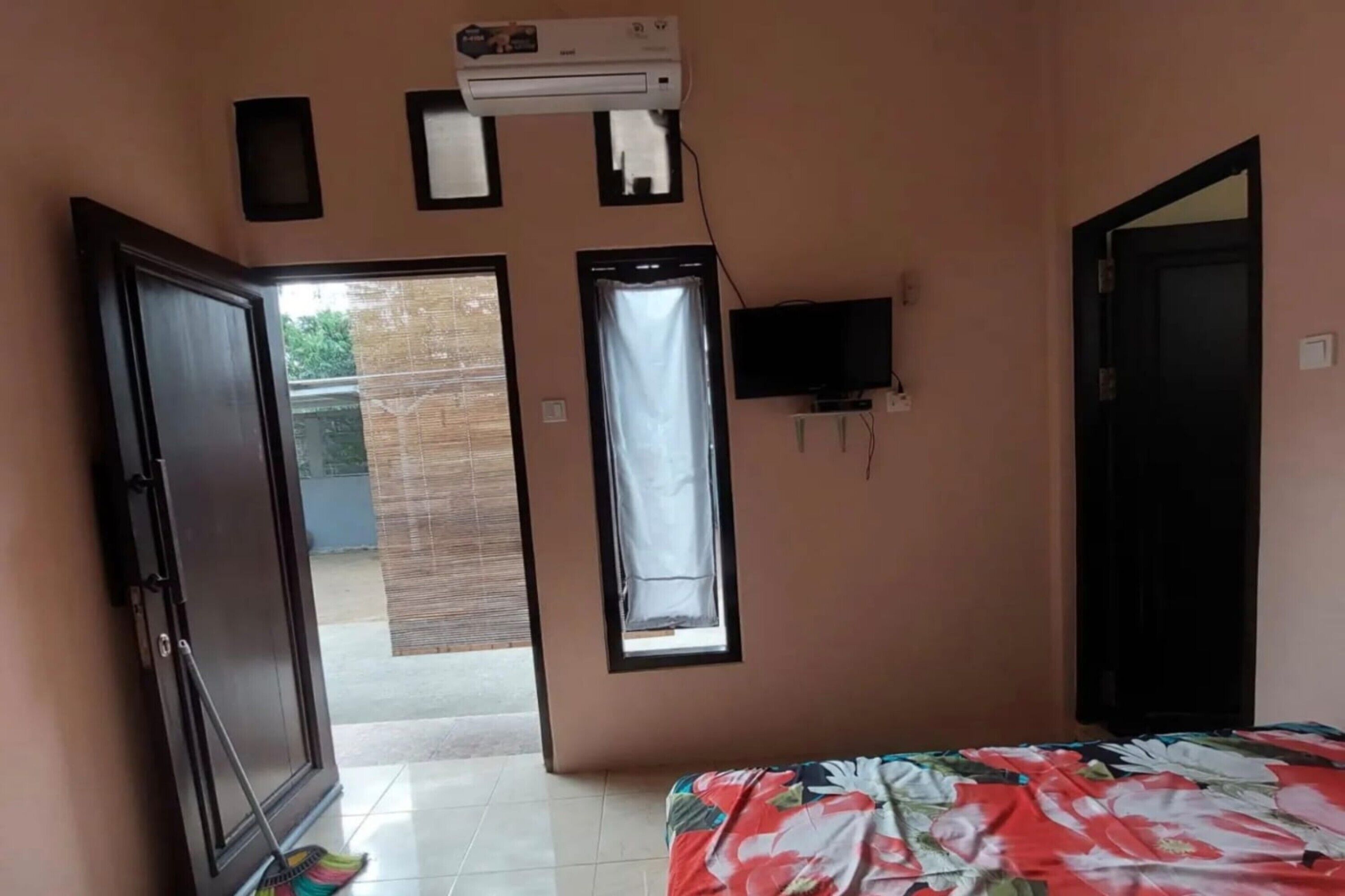A room with a bed, an air conditioner, a window, and a door.