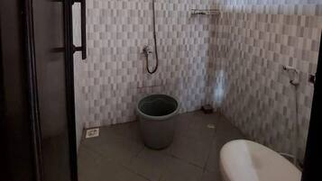 Un baño pequeño con inodoro, ducha y un cubo de basura.