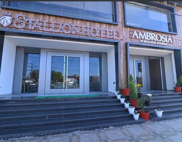 Stallion Hotel and Ambrosia restaurant features a modern facade with a sleek entrance and a wooden accent wall.