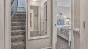 A bedroom with a bed, a nightstand, a lamp, and a wall clock. - Mid-GoodnightVenture (Colorado Springs)