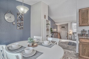 Enjoy meals in this stylish dining area with a round table for four, a wall-mounted clock, and a decorative light fixture.