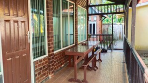 A covered outdoor area with a wooden bench, a brick wall, and a metal gate. - Hotel O Guest House Zidan 21 (Tanahgrogot)