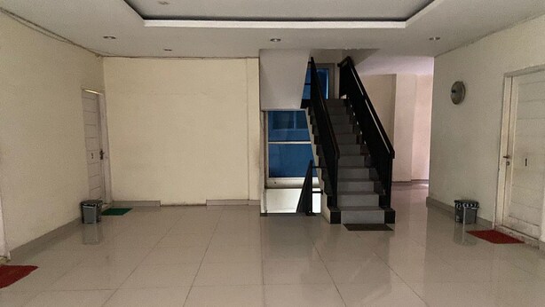 A spacious hallway with a staircase leading to an upper floor. The walls are plain, and the floor is tiled. - Hotel O Guest House Zidan 21 (Tanahgrogot)